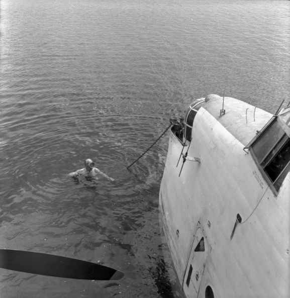PR2183-R2-7-59 Salvage of Maritime Operational Conversion Unit Sunderland, NZ4111, after it was holed and sank in Te Whanga Lagoon, Chatham Islands. Wing Commander Henry Lionel Homer, Director of Aircraft Engineering, doing an exterior underwater inspection of the Sunderland. NB. This negative deteriorating resulting in poorer image quality.