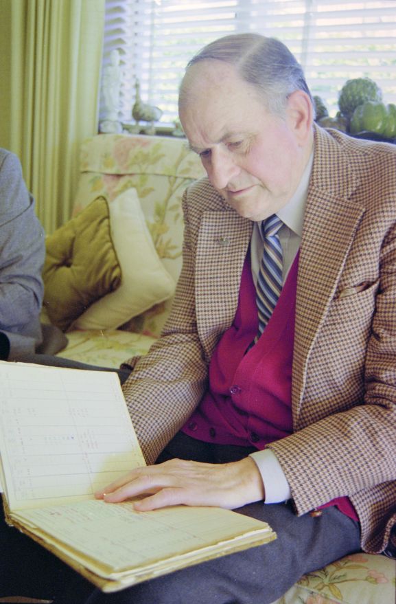 PF236-7-94 Portrait of Air Vice Marshal (retired) CL Siegert looking at his log book.