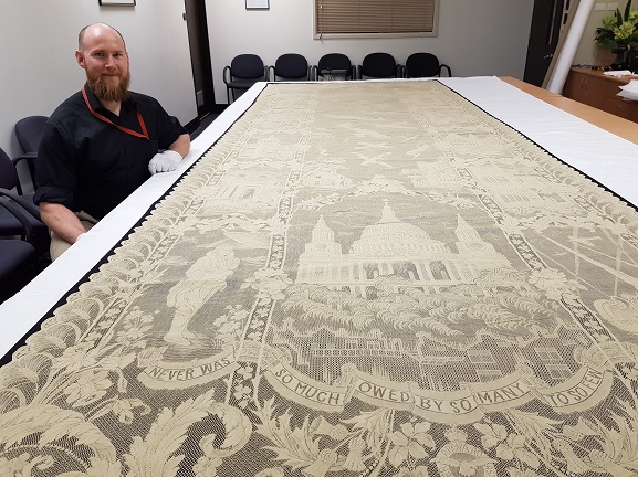 Murray with Battle of Britain Lace Panel Collections Technician Murray McGuigan with the Battle of Britain Lace Panel in the collection of the Air Force Museum of New Zealand.