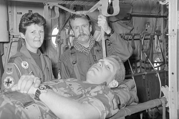 PD12-28-91 Corporal John Felton acts as patient on a stretcher in a No. 40 Squadron Hercules fitted out for aeromedical evacuation, with Squadron Leader Pauline Gwyther (No. 4626 Aeromedical Squadron, RAF) and Air Loadmaster Gary Porteous. Believed to be at Riyadh, Saudi Arabia, Feb-Mar 1991. Image ref PD12-28-91, RNZAF Official.